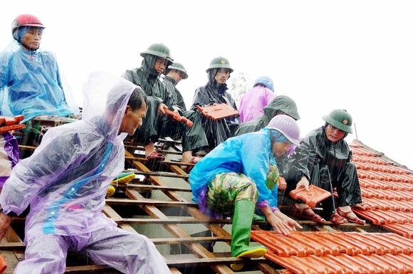 Lực lượng chức năng giúp người dân ở xã Thịnh Lộc (huyện Lộc Hà, tỉnh Hà Tĩnh) lợp lại mái nhà sau mưa bão. Ảnh: DƯƠNG QUANG