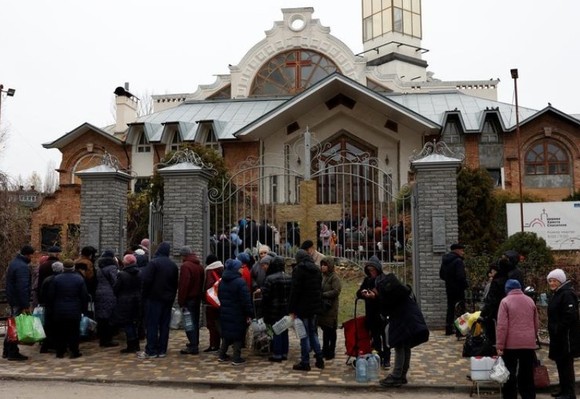 Người dân Kherson xếp hàng nhận hỗ trợ thực phẩm và nước bên ngoài một nhà thờ ngày 22-11. Ảnh: REUTERS