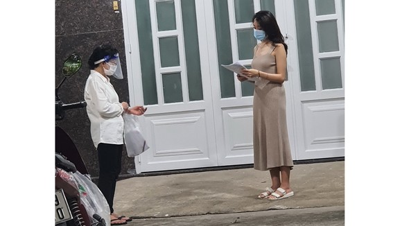  Bà Lê Thị Ngọc Bối (trái), Tổ trưởng Tổ 46 (khu phố 3,  phường 19, quận Bình Thạnh) đến nhà phát phiếu đăng ký  tiêm vaccine cho người dân