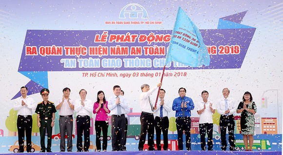Chủ tịch UBND TPHCM Nguyễn Thành Phong trao cờ phát động ra quân thực hiện năm An toàn giao  thông 2018. Ảnh: QUỐC HÙNG
