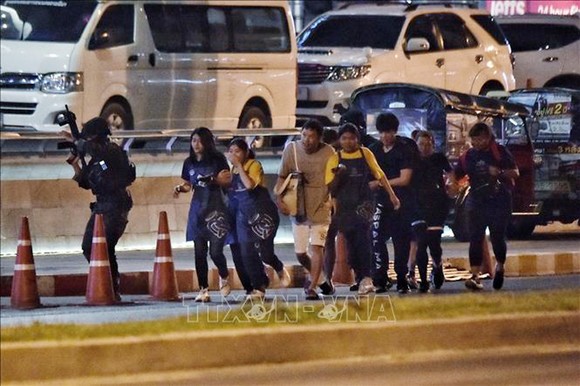 Các con tin được lực lượng an ninh Thái Lan hỗ trợ rời khỏi trung tâm thương mại Terminal 21, nơi nghi phạm Jakrapanth Thomma vụ xả súng và bắt giữ con tin. Ảnh: AFP/TTXVN