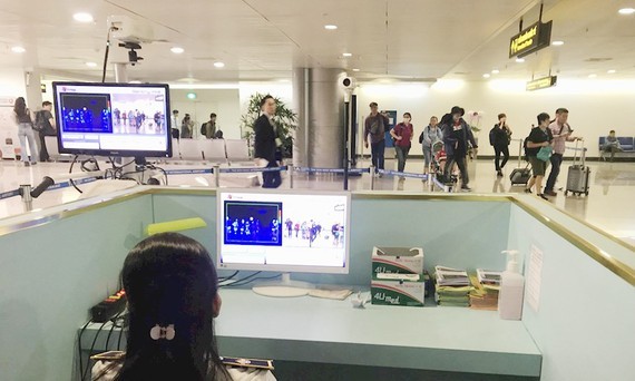 Nhân viên sân bay Tân Sơn Nhất kiểm tra màn hình hiển thị máy quét thân nhiệt đối với hành khách quốc tế đến Việt Nam. Ảnh: TTXVN
