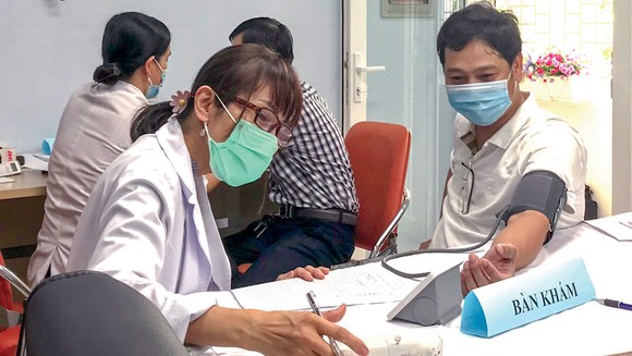 Nhân viên y tế đo huyết áp cho người dân trước khi tiêm vaccine phòng Covid-19