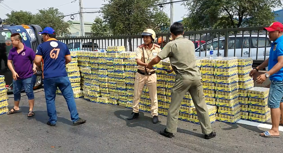 Người dân cùng CSGT dọn hàng trăm thùng nước ngọt giúp tài xế. Ảnh: CHÍ THẠCH 