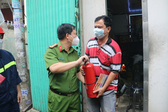 Đại tá Huỳnh Quang Tâm, Trưởng phòng PC07 trao bình chữa cháy cho người dân. Ảnh: C.T