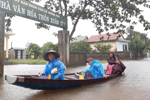 Người dân huyện Quảng Điền, tỉnh Thừa Thiên - Huế  di chuyển trên đường ngập lụt, chiều 17-10. Ảnh: VĂN THẮNG