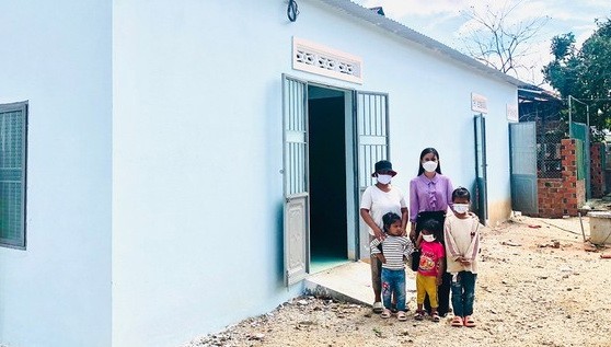 黃氏妙鸞老師與一名貧困學生在新房屋前合影。
