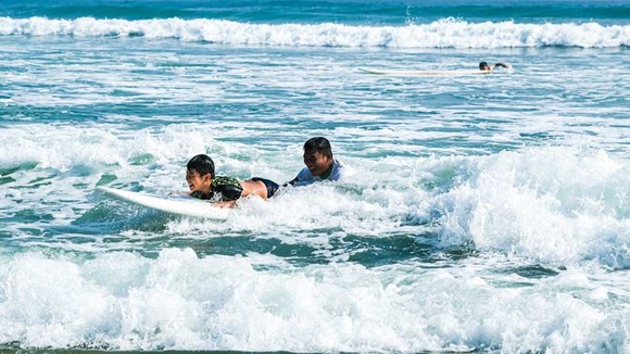 某小朋友在廣南省會安市安龐海上戴著浮袖學習衝浪。